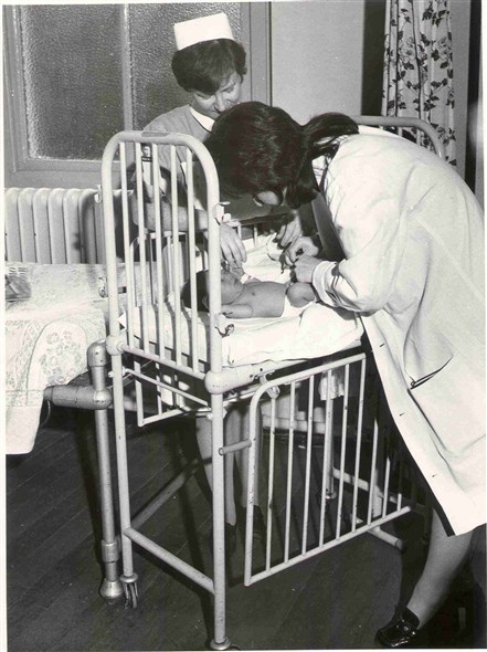 Photo:Nurse and doctor examining an infant, 1970 (catalogue reference: SBHF/PG/28)