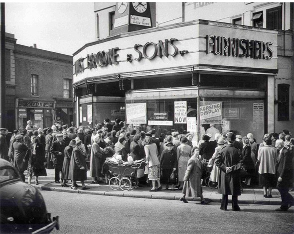 Photo:A window display in a furniture shop on the corner of Lower Clapton Road and Clarence Road, watched by a large crowd of people. Posters in the window read "your hospital needs your help now" and "Nursing display", Apr 1955 (Catalogue reference: SBHH-PG-181).